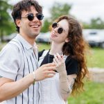 Young couple laughing outdoors on a sunny day.