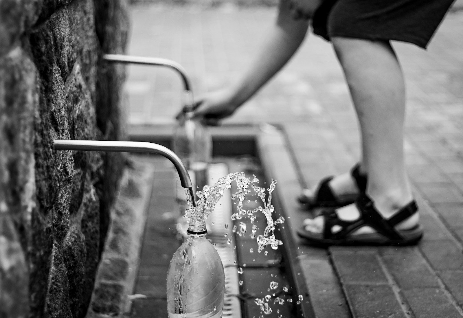 person putting bottles under faucets