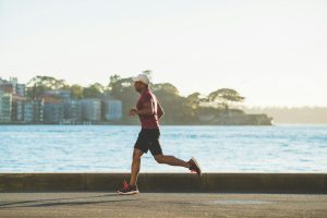 Runner che corre all'aperto, simbolo di benefici del running e dell'importanza di alimentazione e idratazione