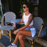 Donna seduta all'aperto al tavolino del bar durante una giornata estiva.