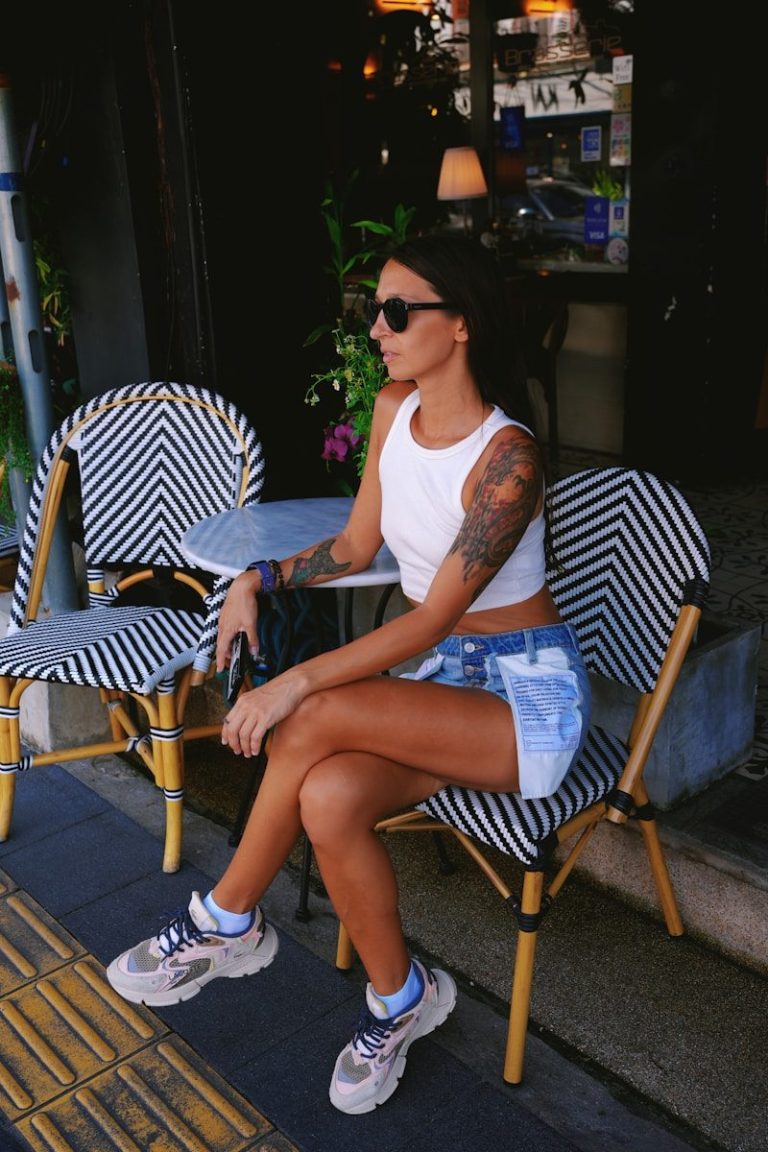 Donna seduta all'aperto al tavolino del bar durante una giornata estiva.