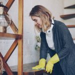 Donna pulisce un mobile di casa con un panno e guanti protettivi.