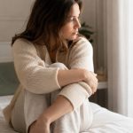 Donna seduta sul letto in un momento di riflessione