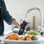 Persona che riempie una borraccia con acqua del rubinetto di casa