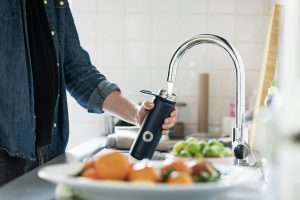 Persona che riempie una borraccia con acqua del rubinetto di casa