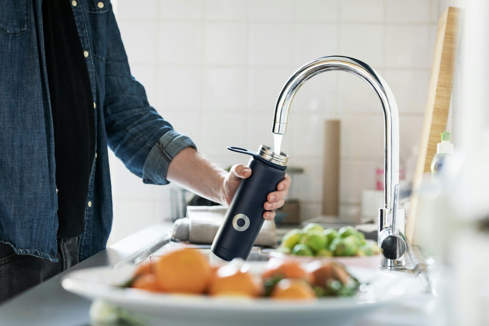 Persona che riempie una borraccia con acqua del rubinetto di casa
