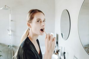 Donna che si lava denti davanti allo specchio del bagno
